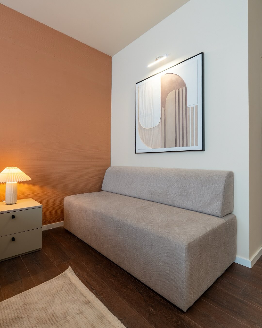 Helles Sofa vor einer Wand in warmen Orange- und Cremetönen